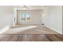 Bright living room featuring neutral carpet, ample natural light, and a ceiling fan at 2958 Oxley St, Strasburg, CO 80136