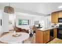 Open-concept living area with wood floors connecting to a breakfast nook, kitchen, and outdoor views at 3663 S Sheridan Blvd # H15, Denver, CO 80235