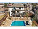 Aerial view of back exterior of luxurious home with a beautiful pool and patio seating at 10057 S Shadow Hill Dr, Lone Tree, CO 80124