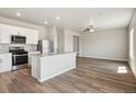 Open-concept kitchen featuring stainless appliances, light countertops and wood floors, seamlessly flowing into the living area at 48195 Shetland Dr, Bennett, CO 80102