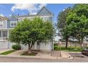 Attractive townhouse featuring a blue exterior, mature trees, and an attached garage in a desirable neighborhood at 1699 S Trenton St # 174, Denver, CO 80231