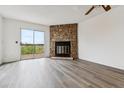 Bright living room with wood-look floors, a stunning stone fireplace, and sliding glass doors to an outdoor deck at 1699 S Trenton St # 174, Denver, CO 80231