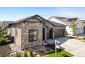 Gray home showcases stone facade, tidy xeriscaping, lawn, and dark trim at 11383 Autumn Moon St, Littleton, CO 80125