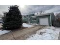 View of two-story house featuring a long driveway, partial snow cover, and mature trees at 1170 W 135Th Dr, Denver, CO 80234