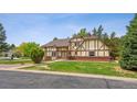 Beautiful front exterior displaying Tudor architecture, mature trees, and manicured lawn at 4855 S Joplin St, Aurora, CO 80015