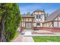 Charming exterior showcasing Tudor-style architecture, green lawn, and mature landscaping at 4855 S Joplin St, Aurora, CO 80015