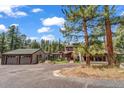 Gorgeous mountain home with oversized two-car garage, mature trees, and asphalt driveway at 32217 Buffalo Park Rd, Evergreen, CO 80439