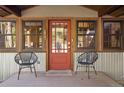 Charming front porch featuring a red door, natural wood trim, and modern metal seating at 32217 Buffalo Park Rd, Evergreen, CO 80439