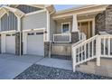Inviting front porch with gray stone accents, white railing, and access to the two-car garage at 651 Scrubjay Cir, Castle Rock, CO 80104