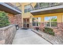 Condo entrance with brick accents, large windows, a well-kept walkway, and manicured landscaping at 9079 E Panorama Cir # 419, Englewood, CO 80112