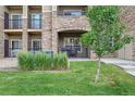 Building exterior with a green lawn, small tree, and units with balconies and a covered patio at 17442 Nature Walk Trl # 105, Parker, CO 80134