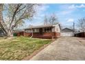 Single-story home with a welcoming front yard, covered porch, extended driveway, and detached garage at 6895 W Oregon Dr, Lakewood, CO 80232
