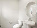 Powder room with pedestal sink, oval mirror, and low-flow toilet at 379 Remuda Rd, Berthoud, CO 80513