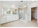Bright bathroom featuring a double vanity, glass shower, and neutral tile flooring at 9322 Quaker St, Arvada, CO 80007