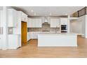Modern kitchen with white cabinets, a large island, stainless appliances, and wood flooring at 9322 Quaker St, Arvada, CO 80007