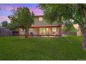 View of the backyard patio with seating, string lights, green lawn and mature trees at 7552 Garland St, Arvada, CO 80005