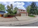 View of a two-story house with an attached two-car garage, driveway, lawn, and wooden fence at 7552 Garland St, Arvada, CO 80005
