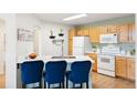 Bright kitchen with modern appliances, quartz counters, and eat-in island with blue chairs, perfect for gatherings at 5735 N Genoa Way # 11-205, Aurora, CO 80019