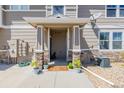 A welcoming front porch with stone pillars, potted plants, and a 'Welcome' mat at 9047 Apache Plume Dr # D, Parker, CO 80134
