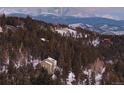 Scenic exterior view of a home nestled in a snow-dusted forest with mountains in the backdrop at 33090 Janelle Cir, Golden, CO 80403