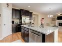 Kitchen island featuring stainless steel dishwasher and granite countertops, plus ample cabinet space at 12513 Grape St, Thornton, CO 80241