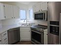 Kitchen with white cabinetry, stainless steel appliances, and a corner window above the sink at 535 High Point Dr, Golden, CO 80403
