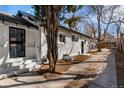 Exterior side view of white painted brick home with trees shading a long walkway on the right at 1858 S Lincoln St, Denver, CO 80210