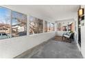 Enclosed sunroom with white brick walls and several windows overlooking the front yard at 1858 S Lincoln St, Denver, CO 80210