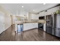 Bright kitchen with white cabinets, stainless steel appliances, and dark hardwood floors at 16643 E 101St Ave, Commerce City, CO 80022