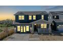 Evening view of a two-story home with lit windows and a welcoming porch at 2980 E 102Nd Pl, Thornton, CO 80229