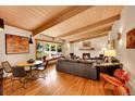 Open-concept living room with hardwood floors, beamed ceilings, and a brick fireplace at 4701 Homestead St, Bow Mar, CO 80123