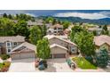 Aerial view of home featuring a well manicured lawn, mature trees, fountain, and two car garage at 16458 W Ellsworth Dr, Golden, CO 80401