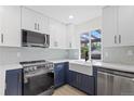 Well-lit kitchen with white and navy cabinets, stainless appliances, and a farmhouse sink at 1238 Rosemary St, Denver, CO 80220