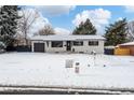 Ranch home with updated exterior, snow covered lawn, and a black fence at 12029 W Dakota Dr, Lakewood, CO 80228