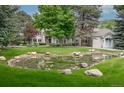 Backyard pond surrounded by lush green grass and mature trees, creating a serene and picturesque outdoor space at 7 Mockingbird Ln, Cherry Hills Village, CO 80113