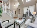 Bright and airy living room with soaring ceilings, large windows, and a staircase, offering a grand and inviting atmosphere at 10062 Eagle Valley Way, Highlands Ranch, CO 80129