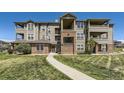 Multi-level condo building showing brick accents, and well-maintained green lawn at 12818 Ironstone Way # 101, Parker, CO 80134