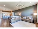 Open-concept living room showcasing a leather sectional, modern chandelier, and adjacent kitchen with bar seating at 3375 New Haven Cir, Castle Rock, CO 80109