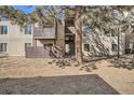 Exterior view of apartments with balconies and a central staircase with a large tree in front at 9995 E Harvard Ave # 246, Denver, CO 80231