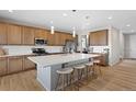 Modern kitchen with a large island, pendant lighting, stainless appliances, and wood flooring at 21650 E Tufts Cir, Aurora, CO 80015