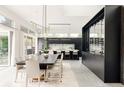 Open-concept dining room with large table, modern lighting, and wine storage, with kitchen in background at 140 S Glencoe St, Denver, CO 80246