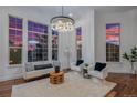 Bright living room featuring hardwood floors, a modern chandelier, and large windows with scenic views at 7821 Inverness Blvd, Englewood, CO 80112