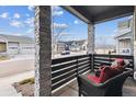 Inviting front porch with stone columns and comfortable wicker seating, offering a relaxing outdoor space at 8403 Rush Creek Ave, Littleton, CO 80125