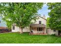 Spacious backyard featuring a lush lawn, mature trees, and a charming covered patio with string lights at 9502 W Hialeah Pl, Littleton, CO 80123