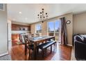 Open dining area featuring a chandelier, wood floors, and sliding glass door to the yard at 10294 E Telluride Ct, Commerce City, CO 80022