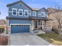 Charming two-story blue home with a two-car garage and well-maintained landscaping at 10294 E Telluride Ct, Commerce City, CO 80022