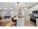 Bright, open kitchen featuring a large island with seating, pendant lighting, and modern stainless steel appliances at 1473 N Locust St, Denver, CO 80220