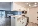 Open kitchen view with breakfast bar, white cabinets, and stainless steel appliances at 3480 S Eagle St # 101, Aurora, CO 80014