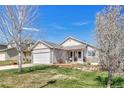 Charming single-story home featuring a well-kept lawn, complemented by stone accents and a blossoming tree at 12868 Capital Creek St, Parker, CO 80134