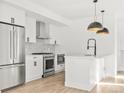 Modern kitchen boasts stainless steel appliances, white cabinets, a functional island, and contemporary hanging light fixtures at 1346 N Knox Ct, Denver, CO 80204